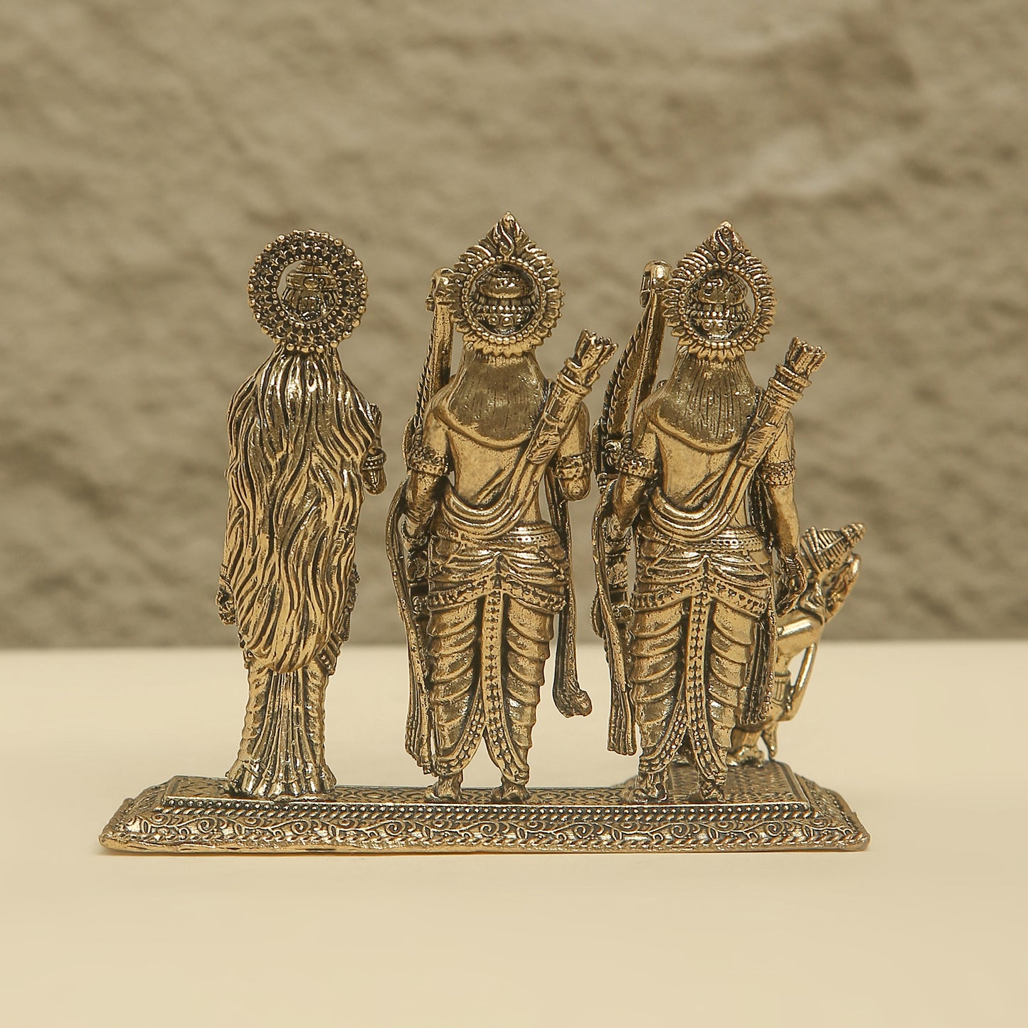Bronze statue of three figures on a beige surface with a brown background