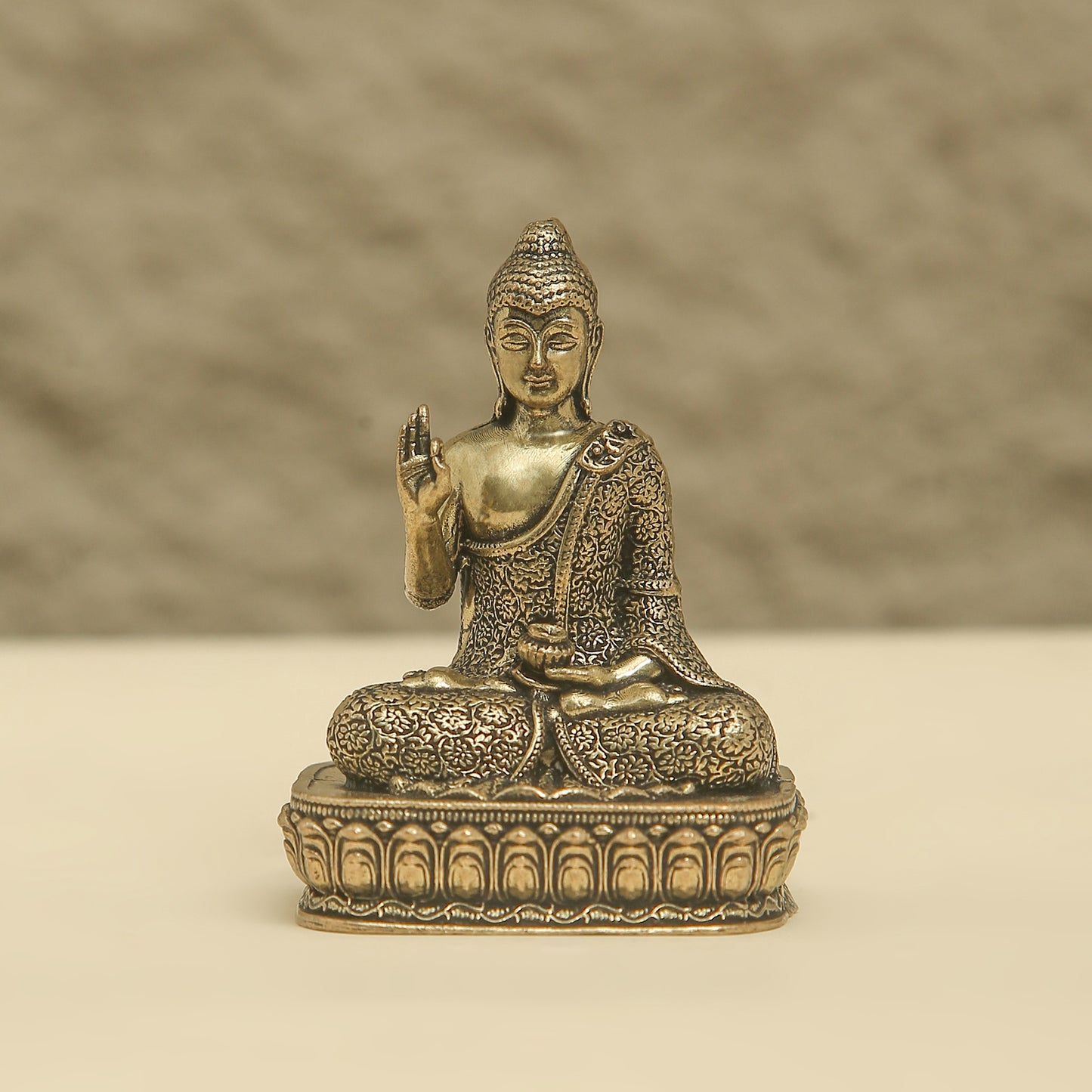 Bronze statue of a seated Buddha on a beige background