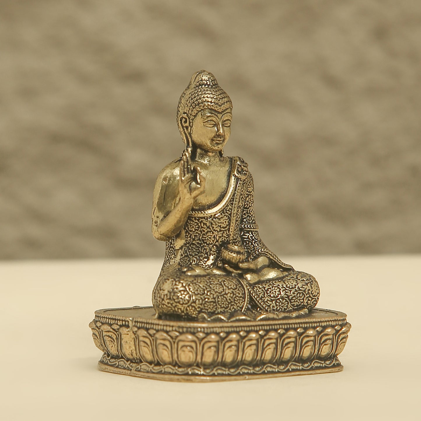 Bronze statue of a seated Buddha on a textured surface