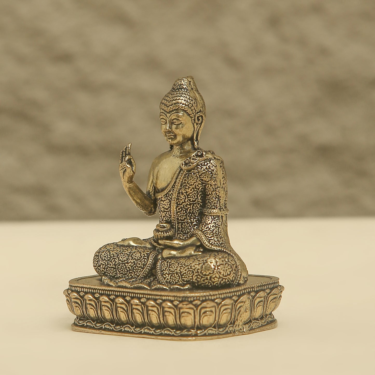 Bronze statue of a seated Buddha on a beige background