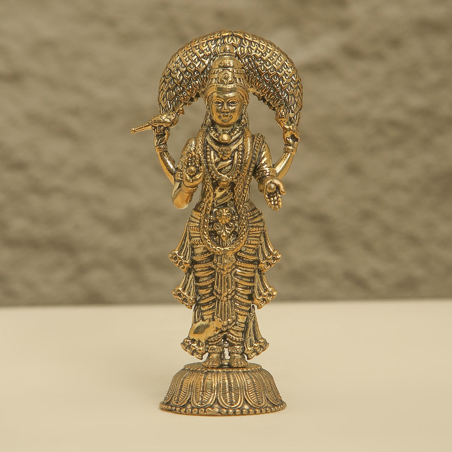 Gold-colored statue of a deity on a beige background