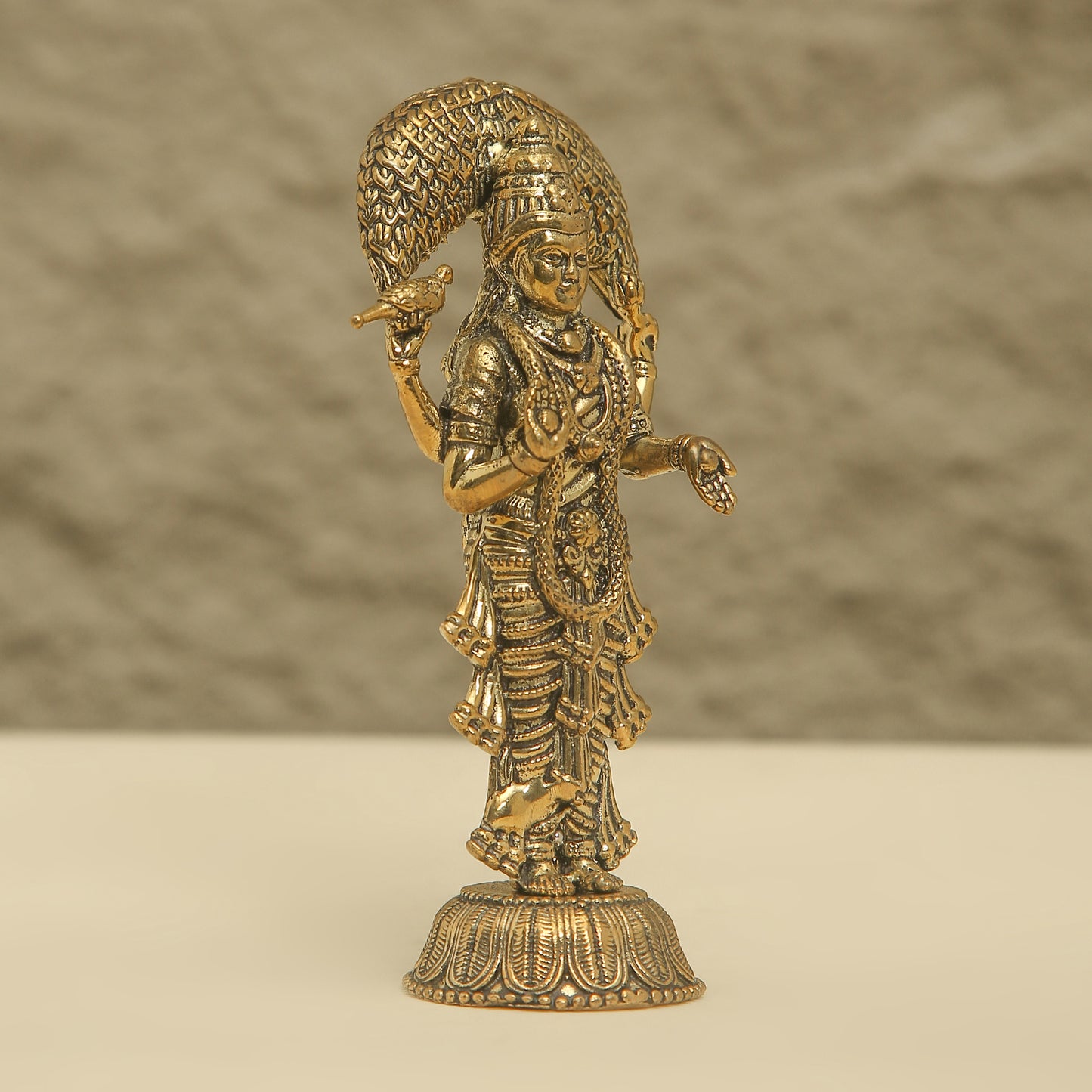 Gold-colored statue of a deity on a beige background