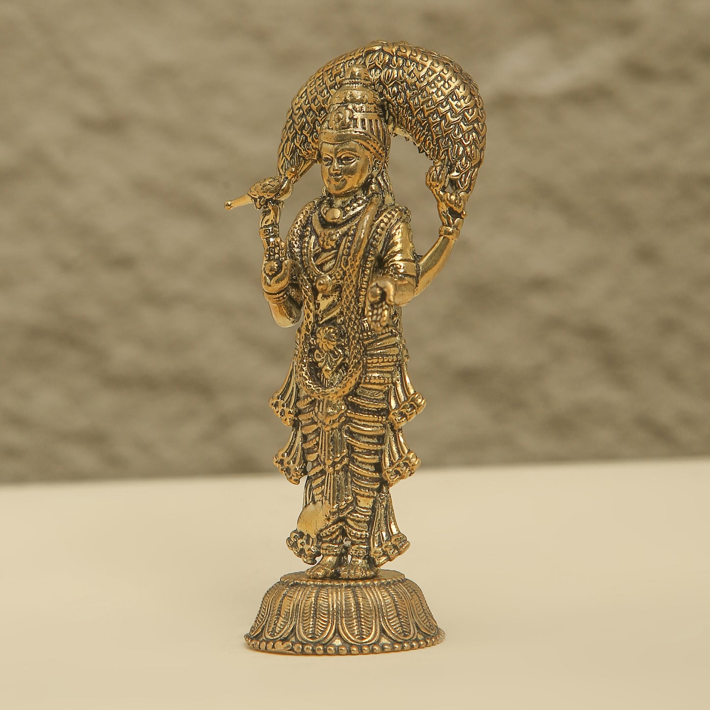 Bronze statue of a deity with intricate details on a beige background