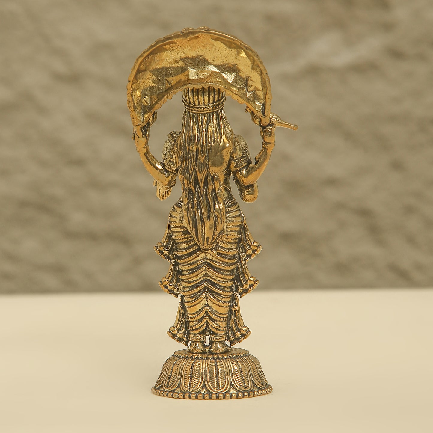 Gold-colored statue of a deity on a beige background