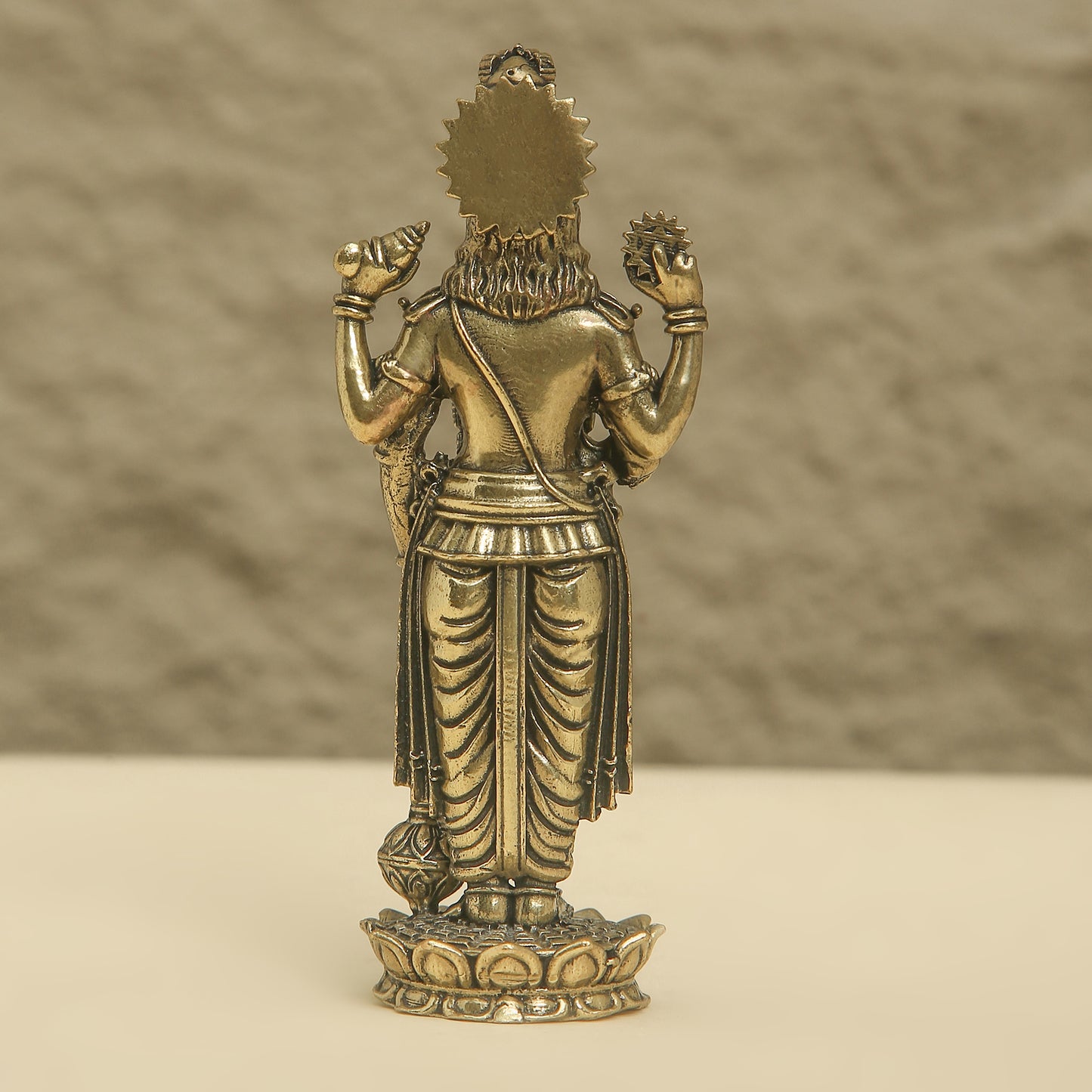 Bronze statue of a deity on a beige surface with a brown background