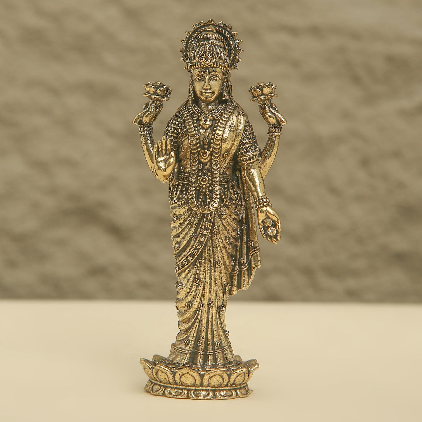 Bronze statue of a deity with intricate details on a beige background