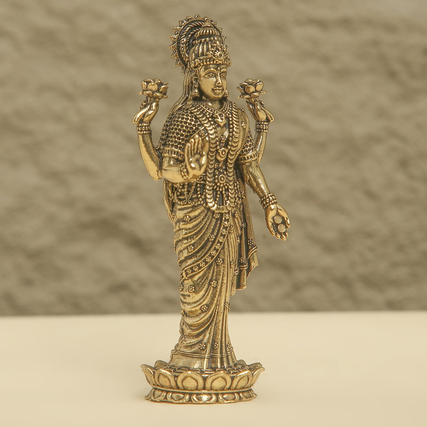 Bronze statue of a deity on a beige surface with a brown background