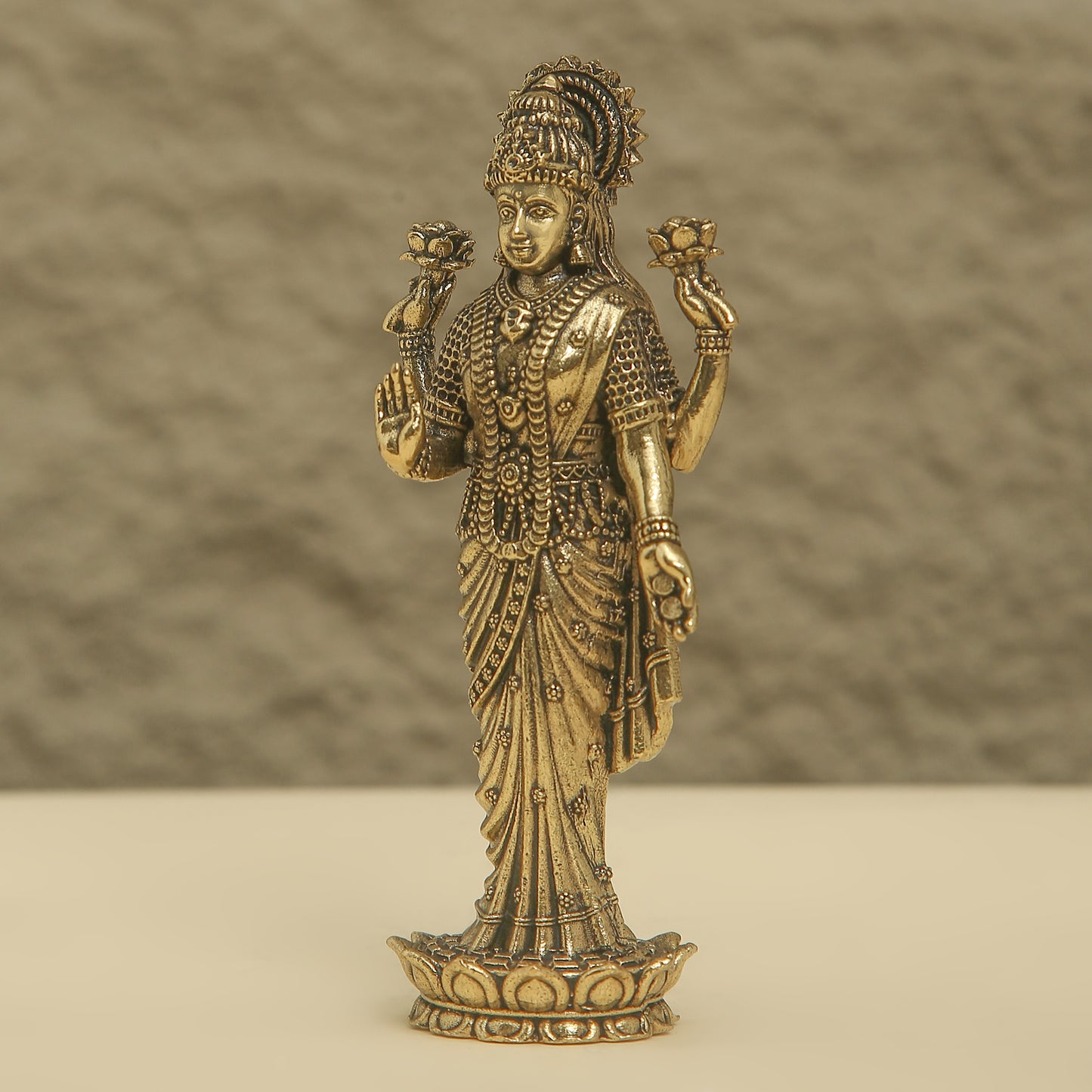 Bronze statue of a deity with intricate details on a beige background