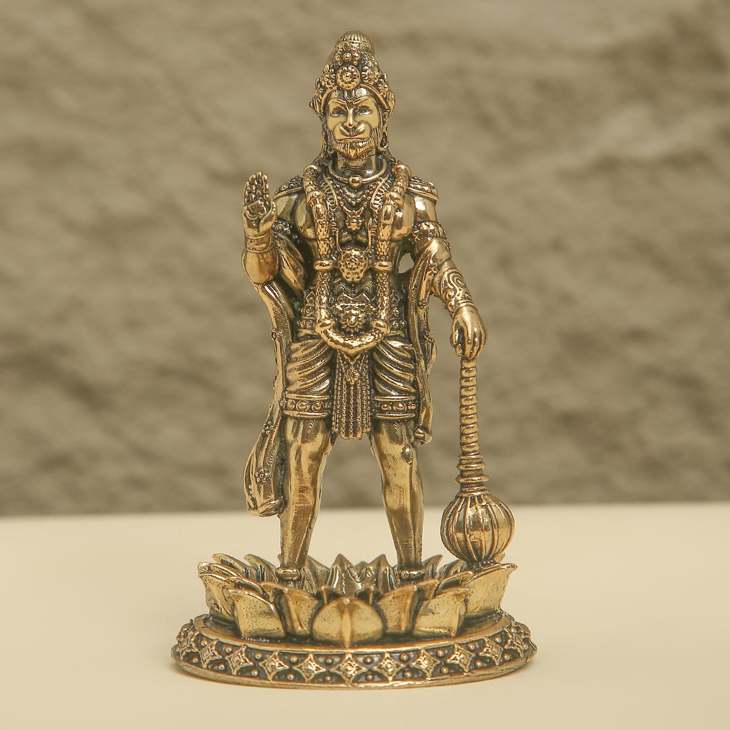 Bronze statue of a deity on a textured surface with a neutral background