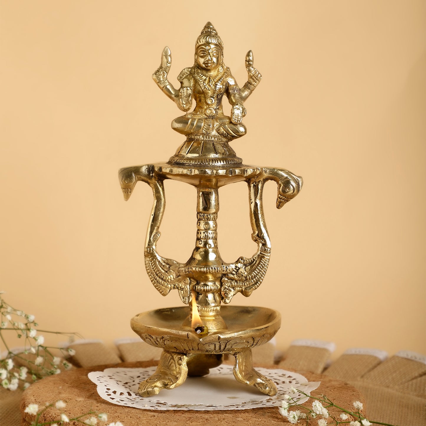 Brass lamp with a deity figure on a beige background