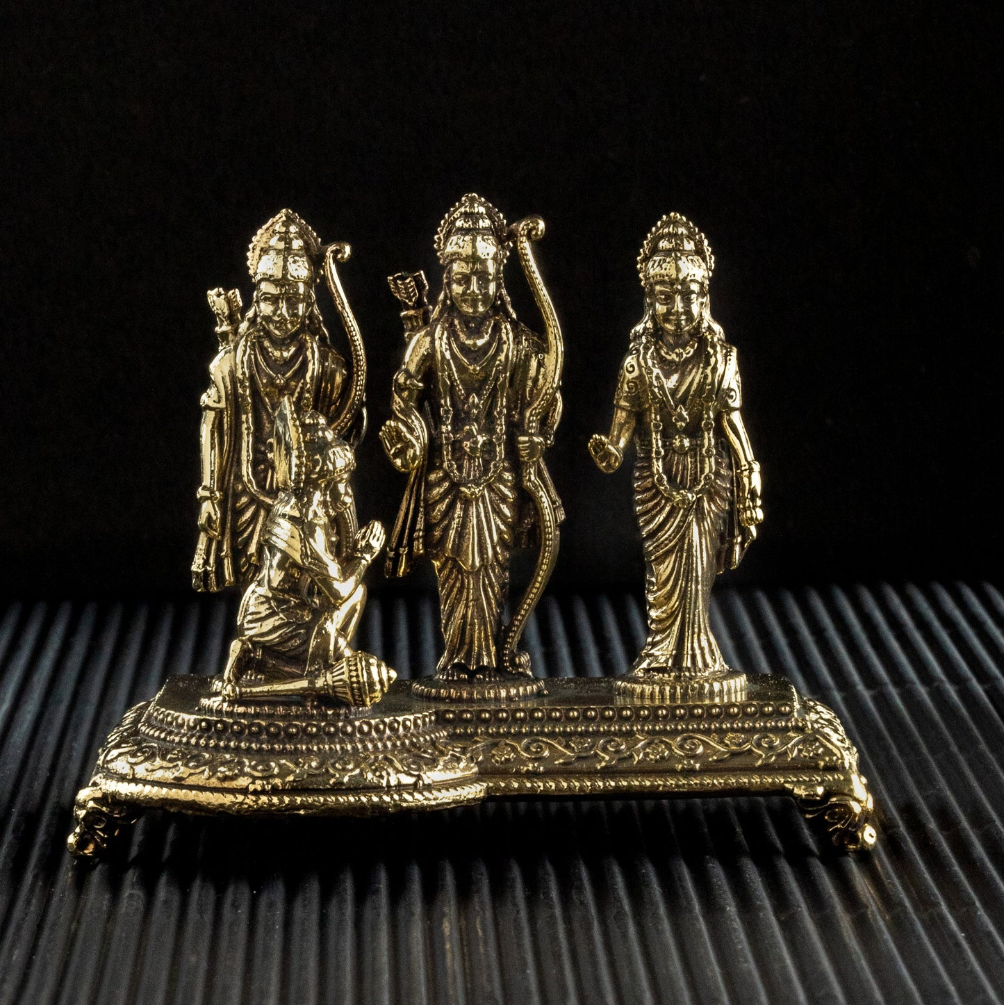 Bronze statue of three figures on a textured black surface
