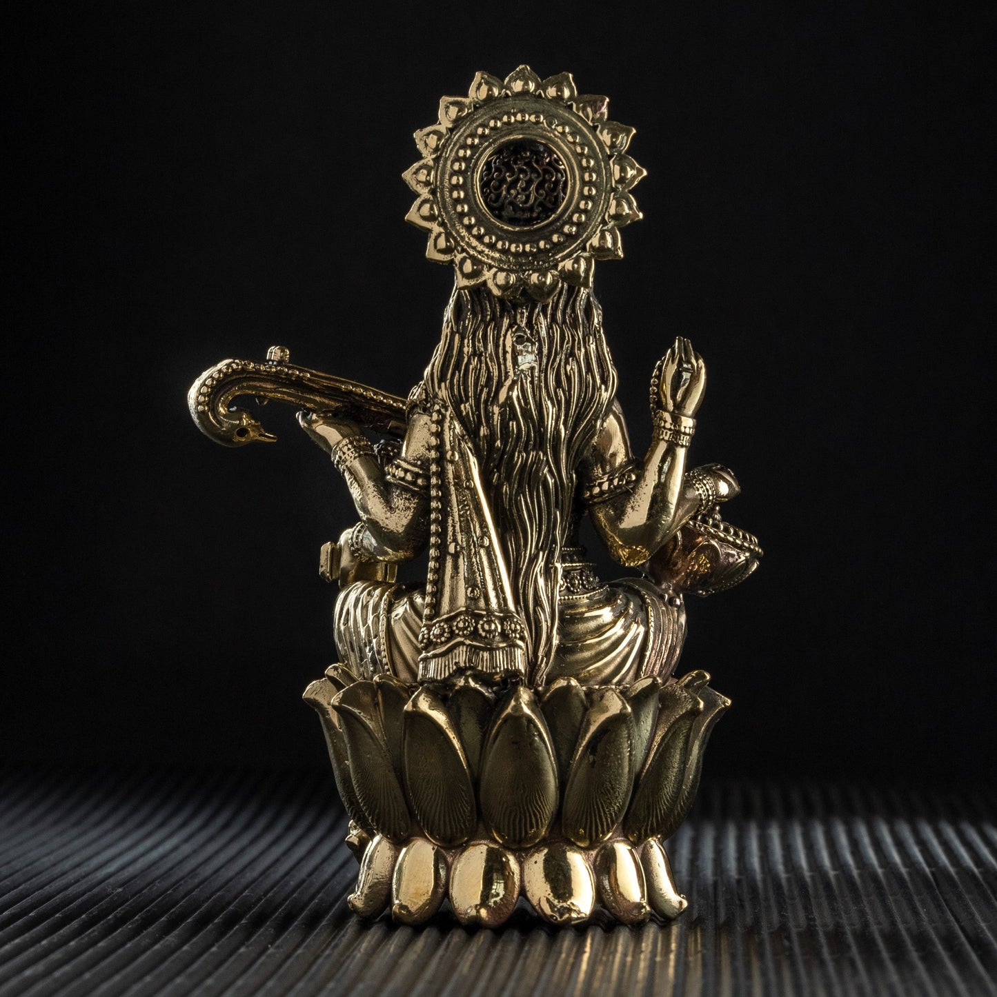 Decorative brass statue on a textured surface with a black background