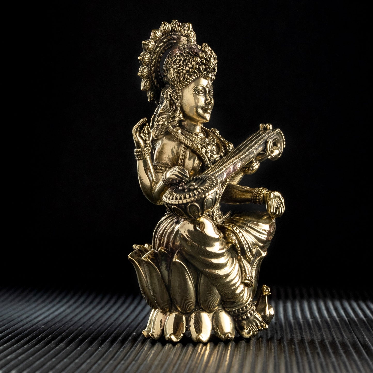Gold statue of a seated figure with a musical instrument on a black background