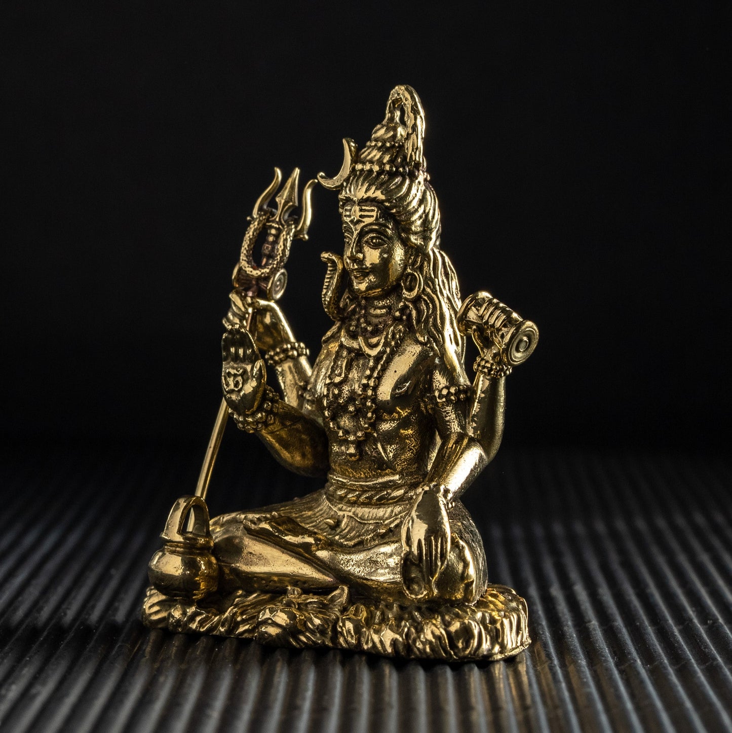 Gold-colored statue of a deity on a textured black surface