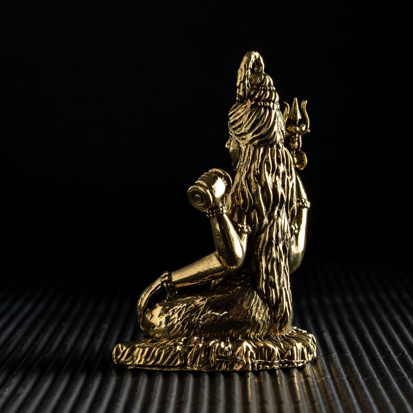 Gold statue of a figure on a textured black surface with a dark background