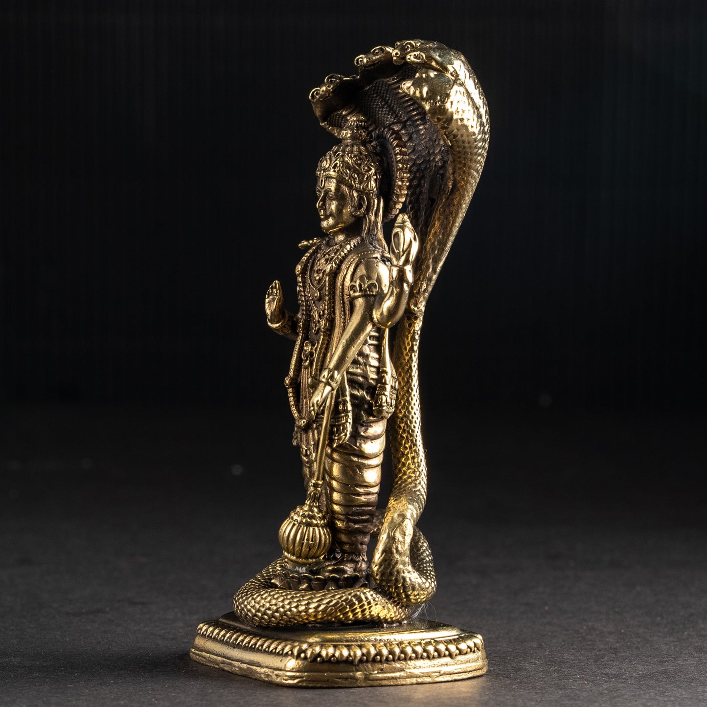 Bronze statue of a figure with a snake on a dark background