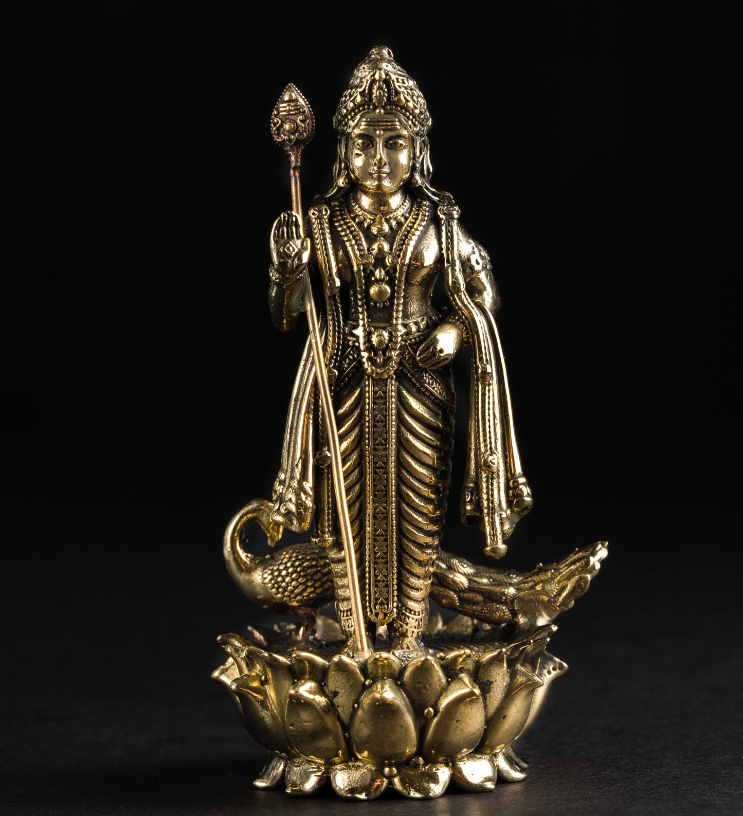 Gold-colored statue of a deity on a black background