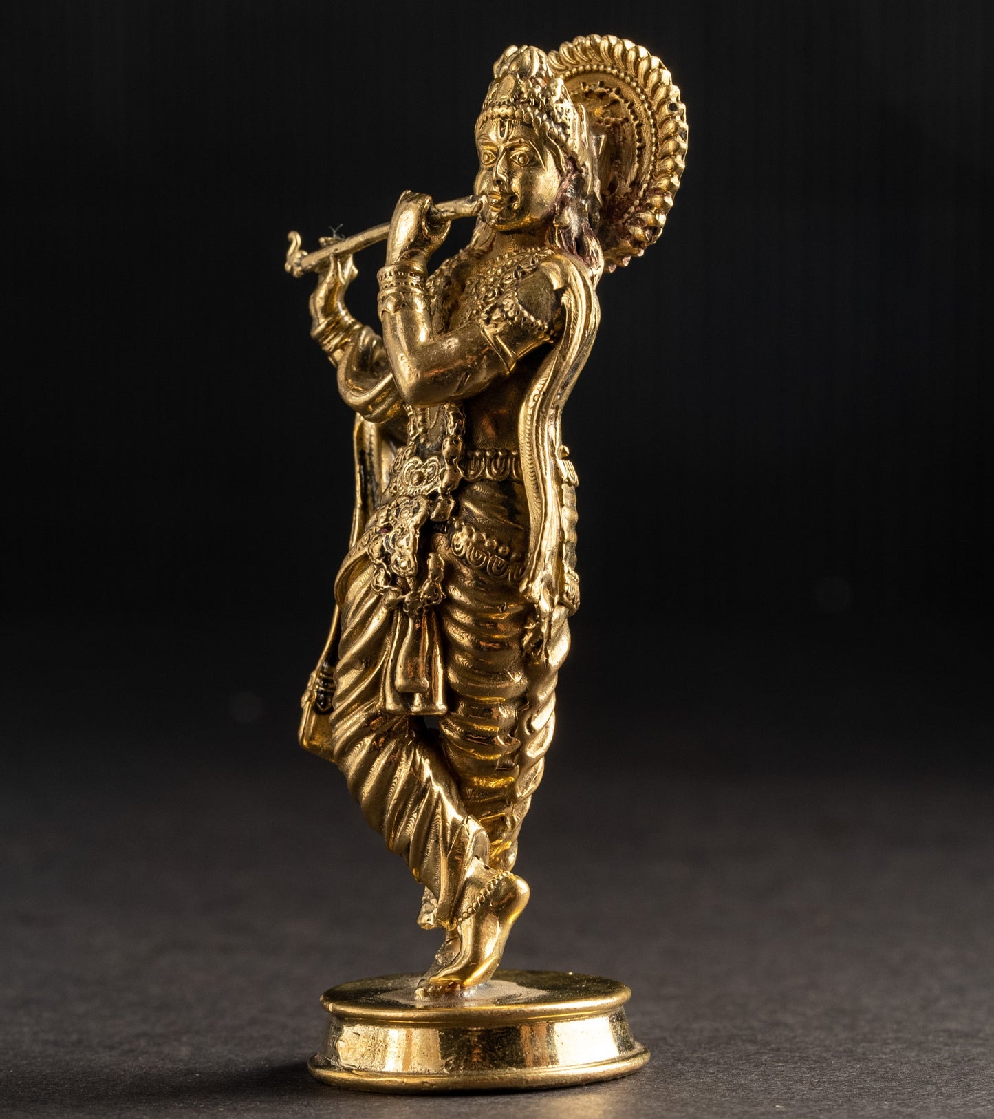 Gold-colored statue of a deity on a black background