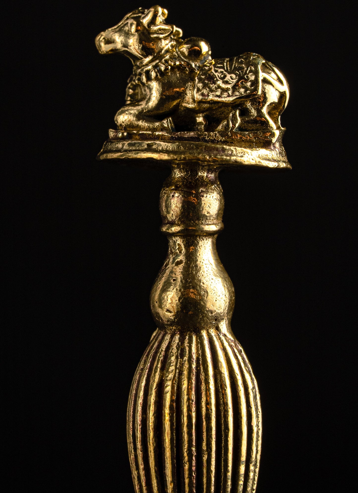 Gold-colored decorative object with a bull figure on a black background