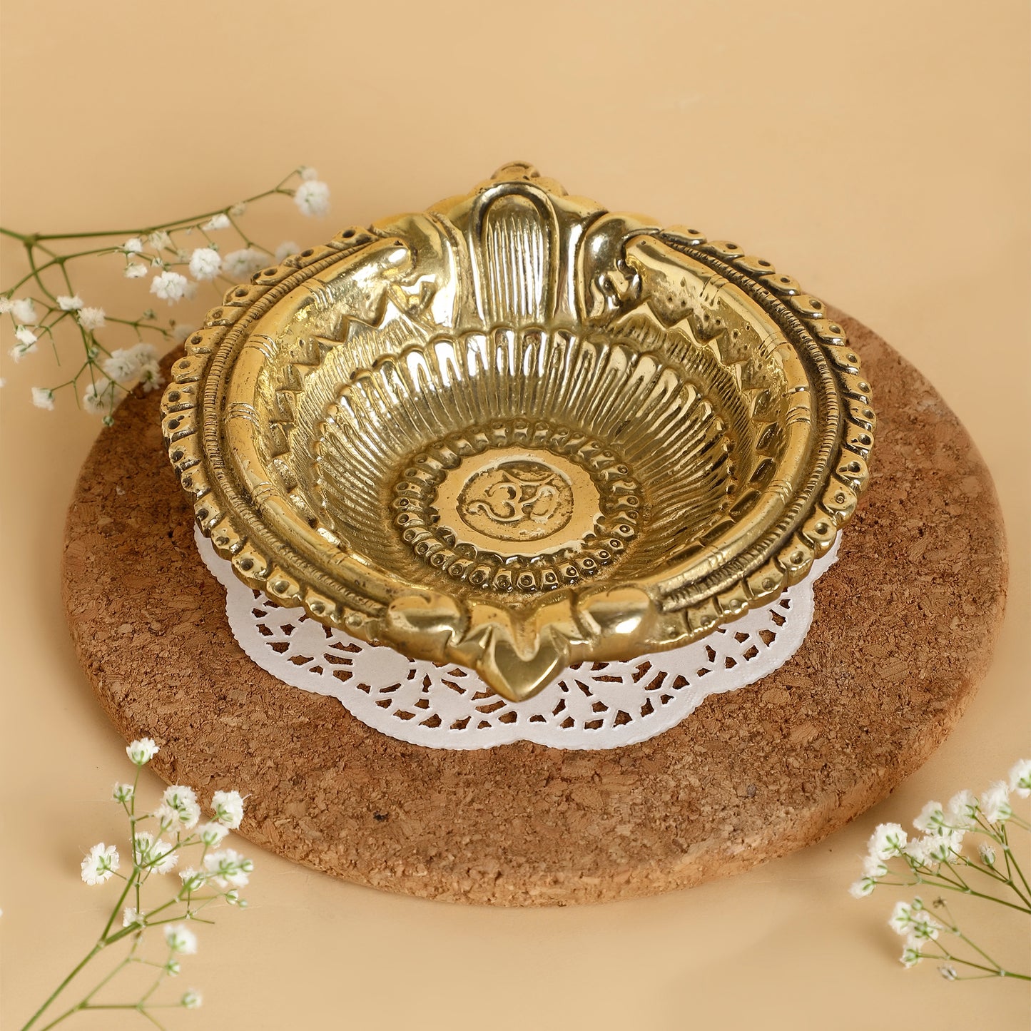 Decorative gold bowl on a cork surface with white flowers