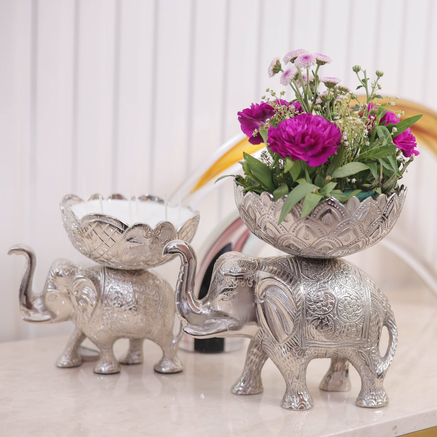 Decorative silver elephant with a bowl of flowers on a light background