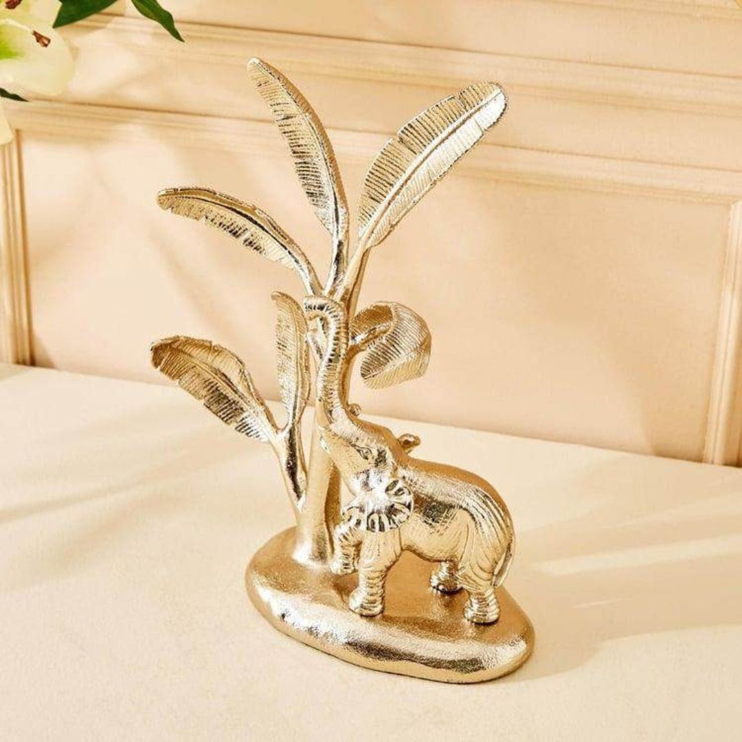 Gold elephant figurine with leaves on a beige surface