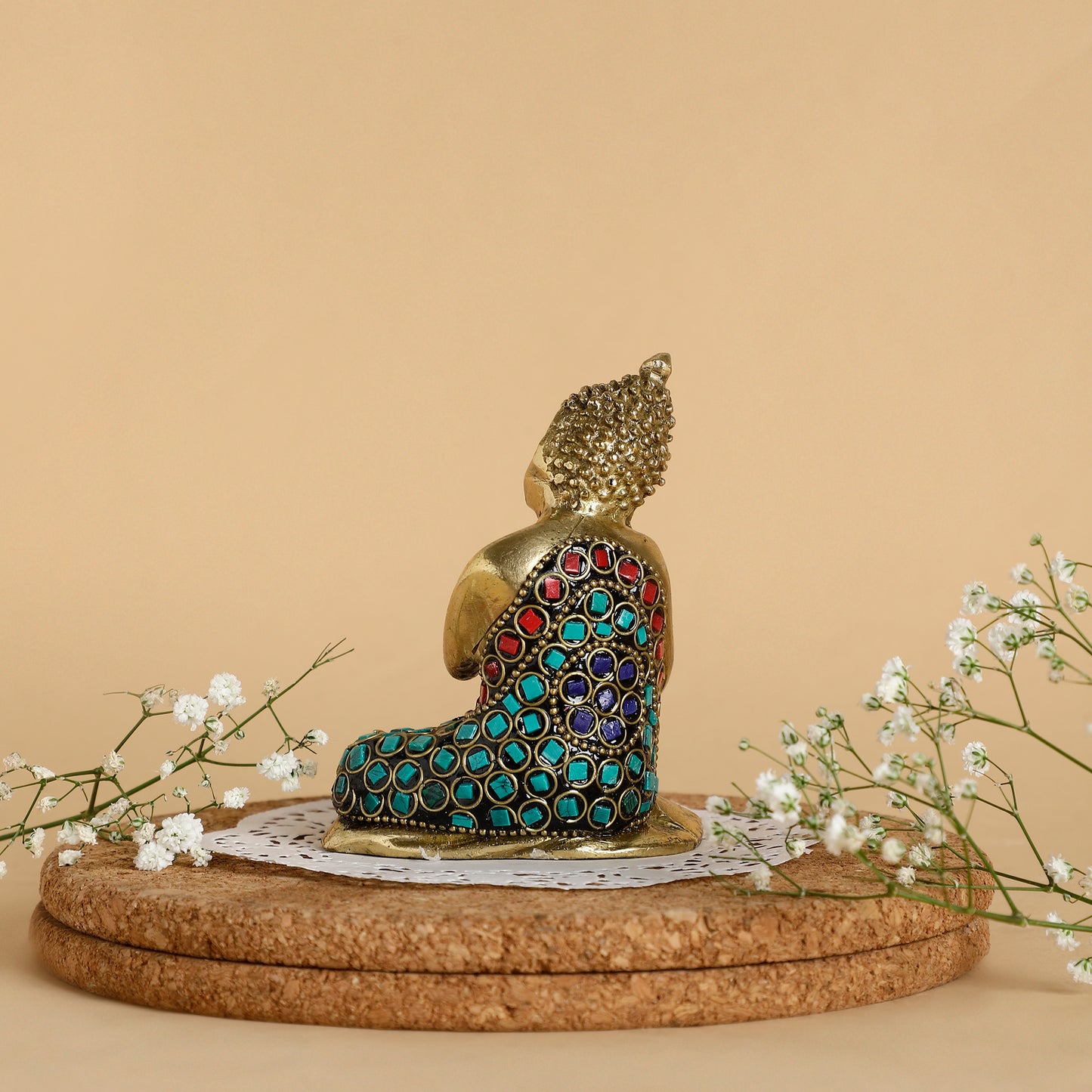 Decorative Buddha statue with gemstones on a cork base against a beige background