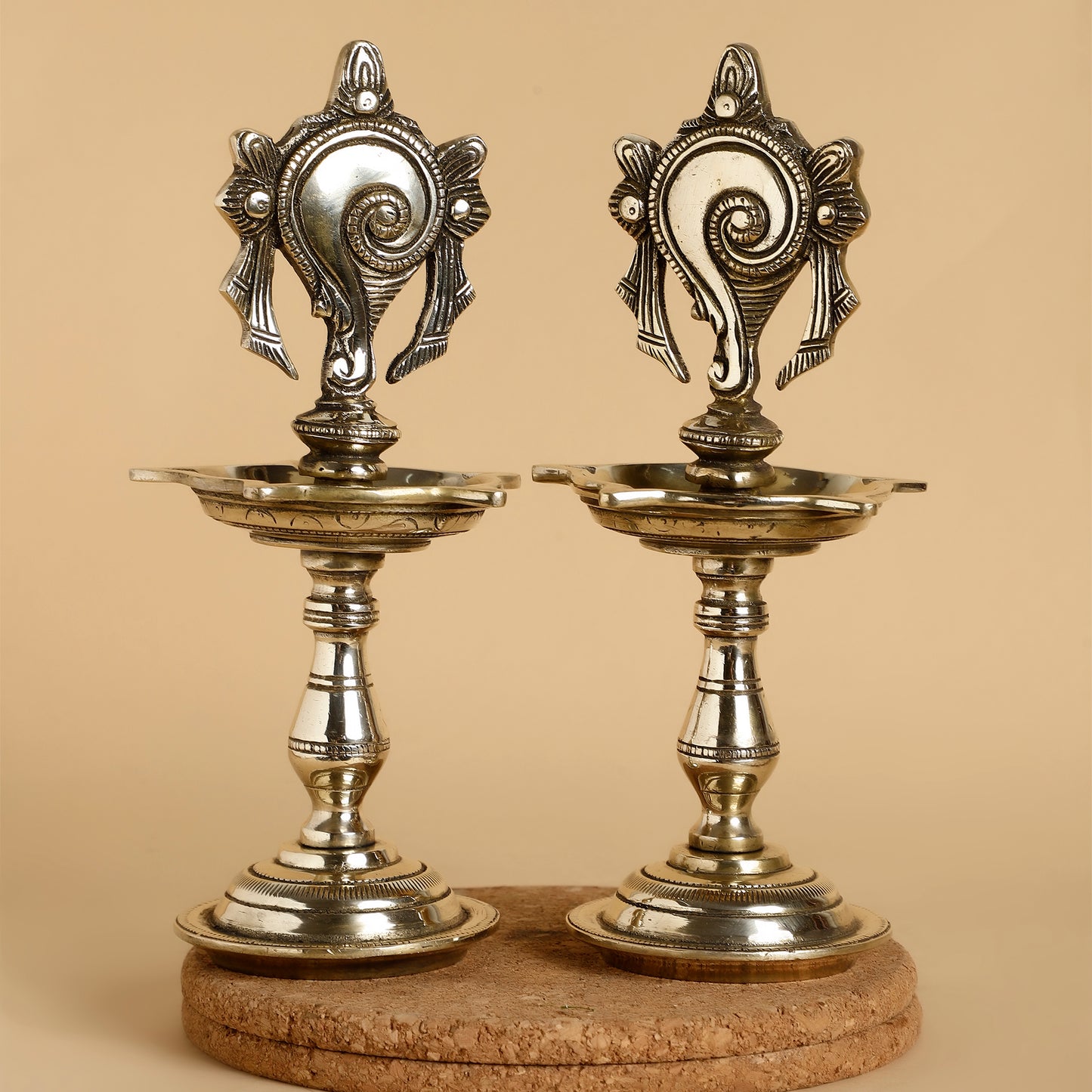 Two ornate silver candle holders on a beige background