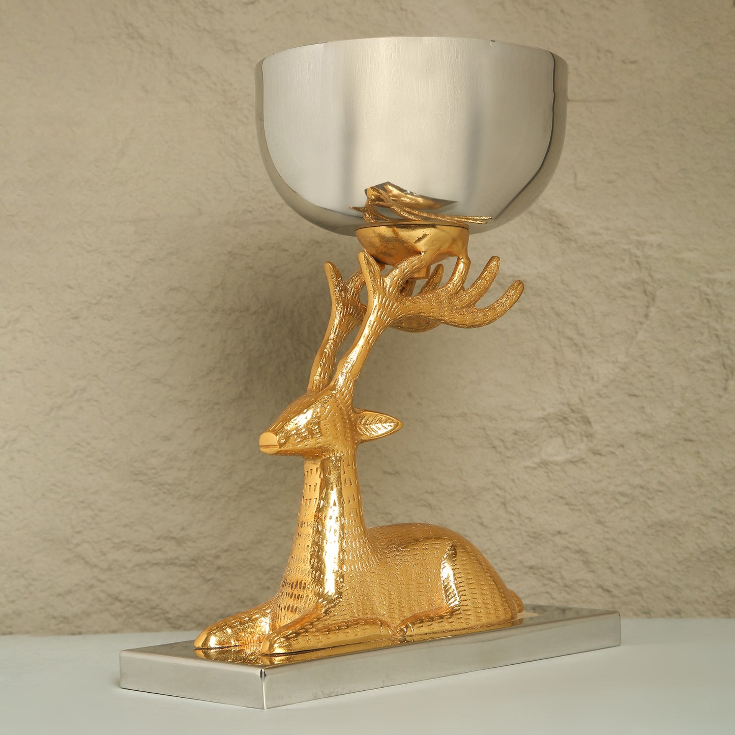 Gold deer-shaped candle holder with a silver bowl on a beige background