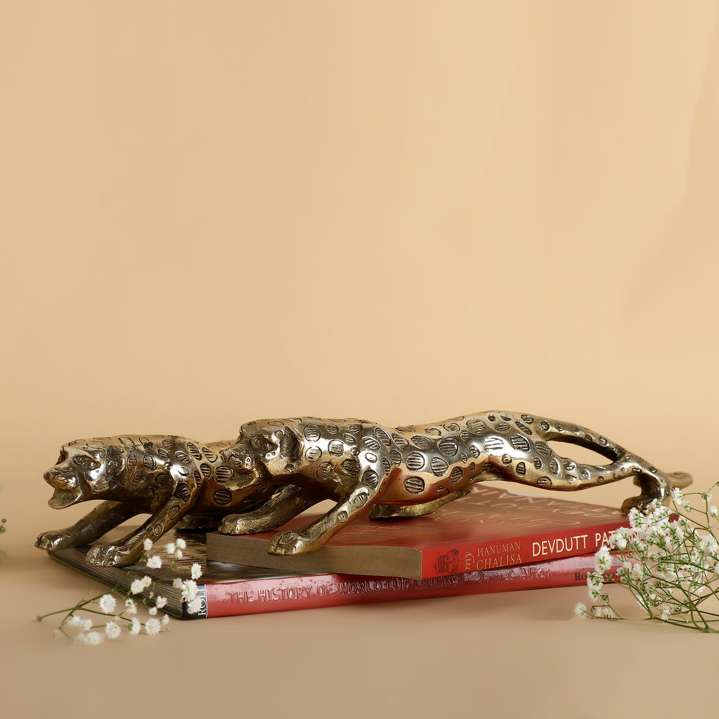 Decorative metallic panther sculpture on books with a beige background