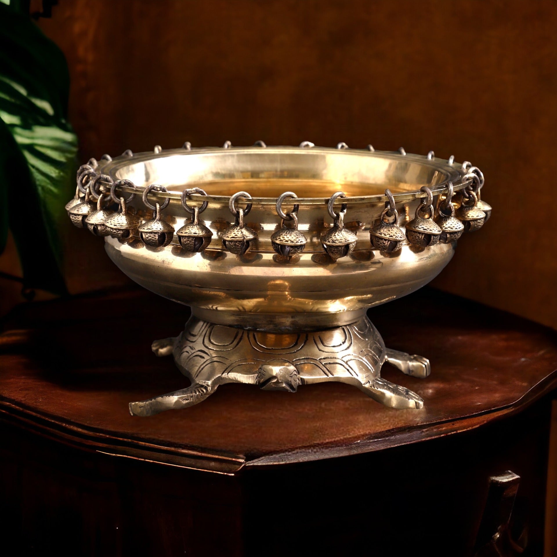 Decorative silver bowl with hanging bells on a wooden surface