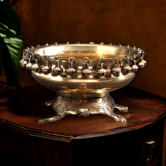 Decorative silver bowl with hanging bells on a wooden surface