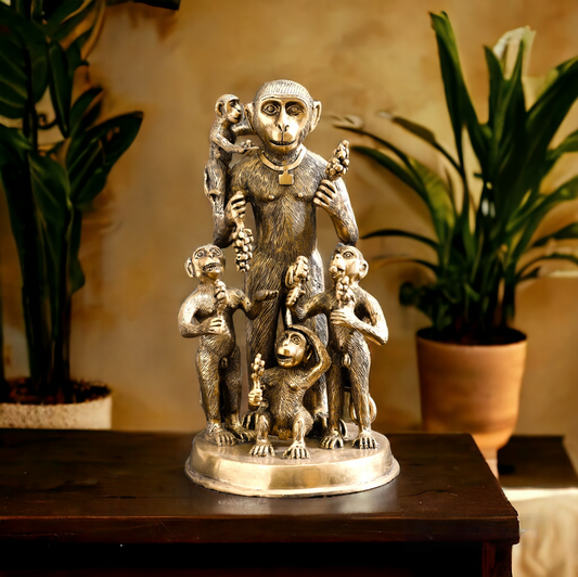 Bronze statue of a monkey with four children on a wooden table, plants in the background