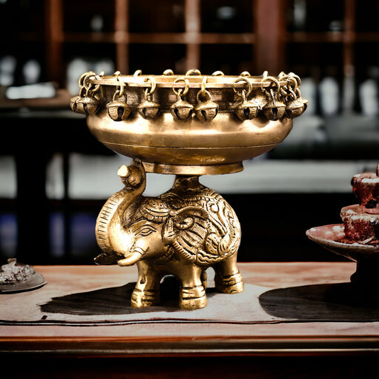 Decorative brass bowl with elephant design on a wooden table