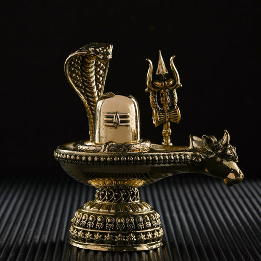 Decorative brass sculpture with snake, trident, and lion on a black background