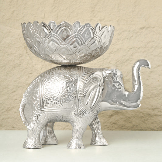 Decorative silver elephant with a bowl on its back against a beige background