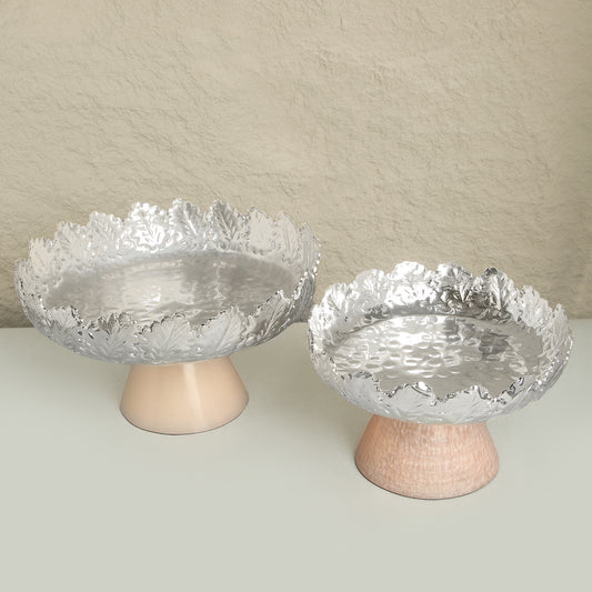 Two glass bowls with textured surfaces on wooden stands against a beige background