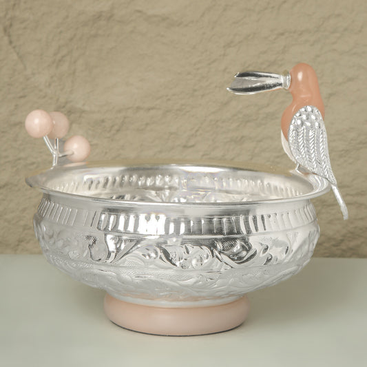 Decorative silver bowl with pink base and handle on a beige background