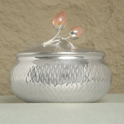 Silver textured container with a decorative lid on a beige background