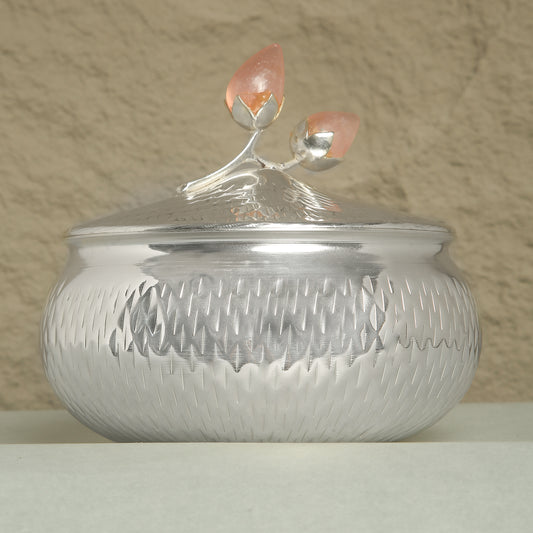 Silver textured container with a decorative lid on a beige background