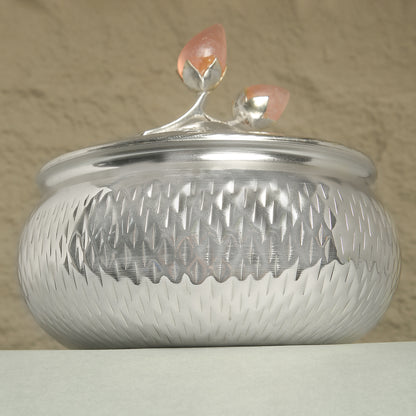 Silver textured container with a decorative lid on a beige background