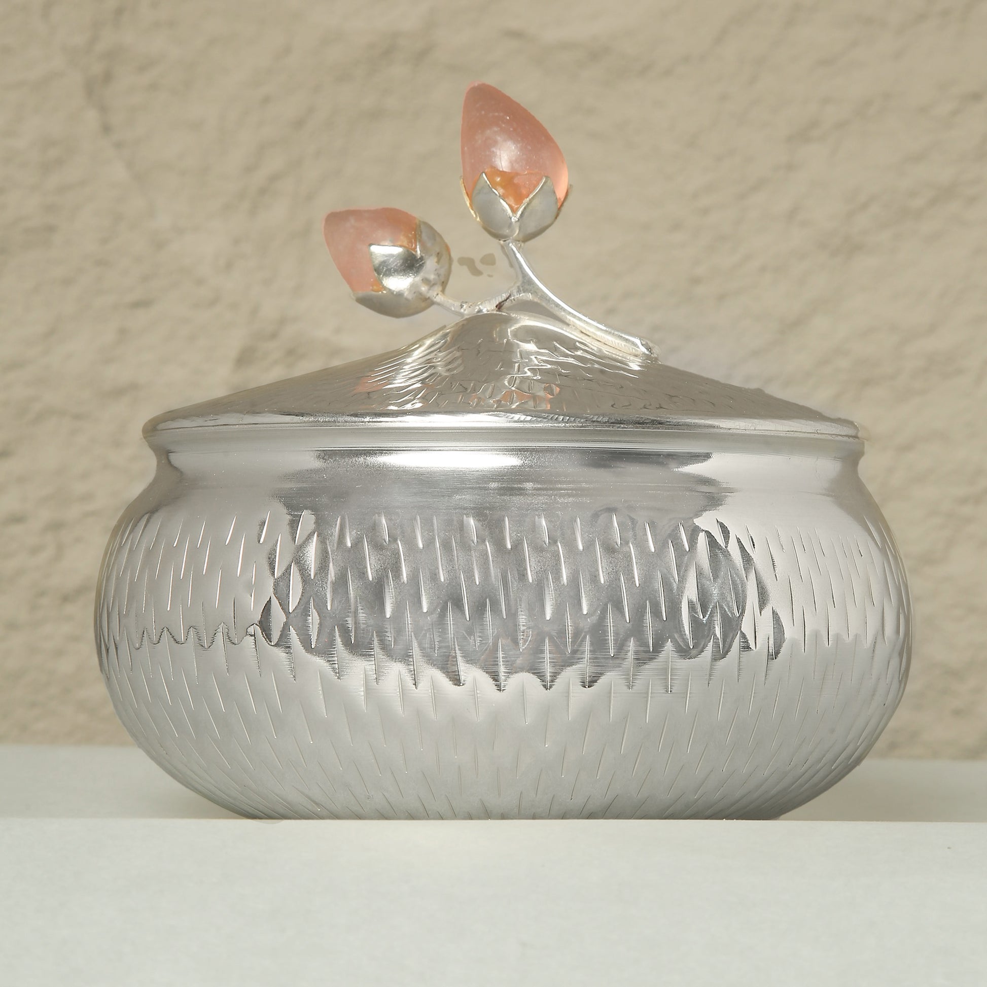 Silver textured container with a lid featuring a flame design on a beige background