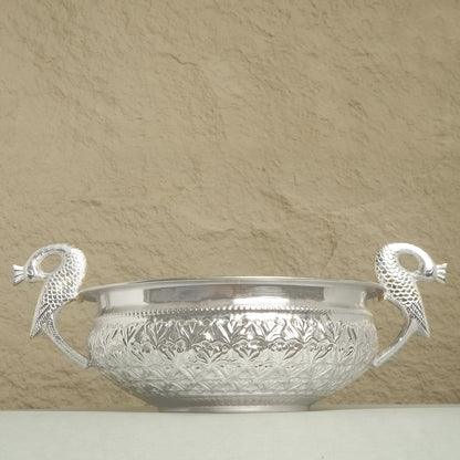 Silver bowl with decorative handles on a beige background