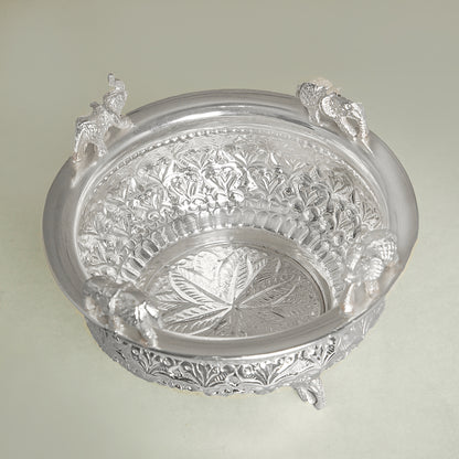 Decorative silver bowl with intricate designs on a light green background