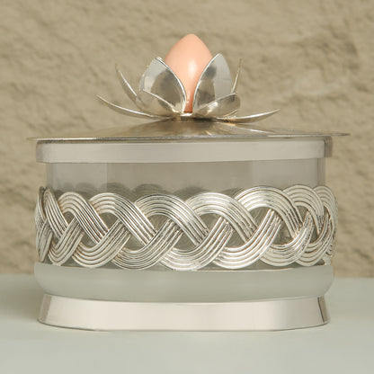 Decorative container with silver lid featuring a floral design on a neutral background