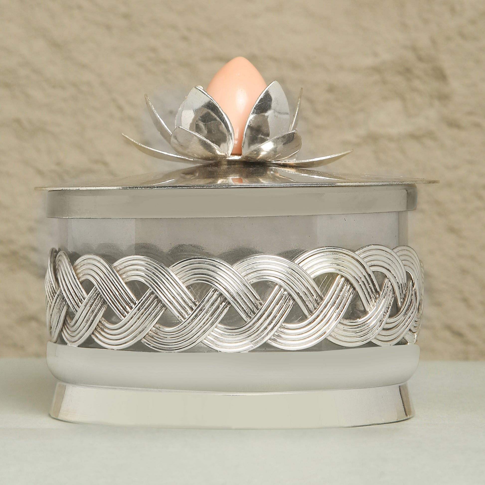 Decorative container with silver lid featuring a floral design on a beige background
