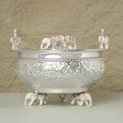 Decorative silver bowl with elephant figures on a beige background