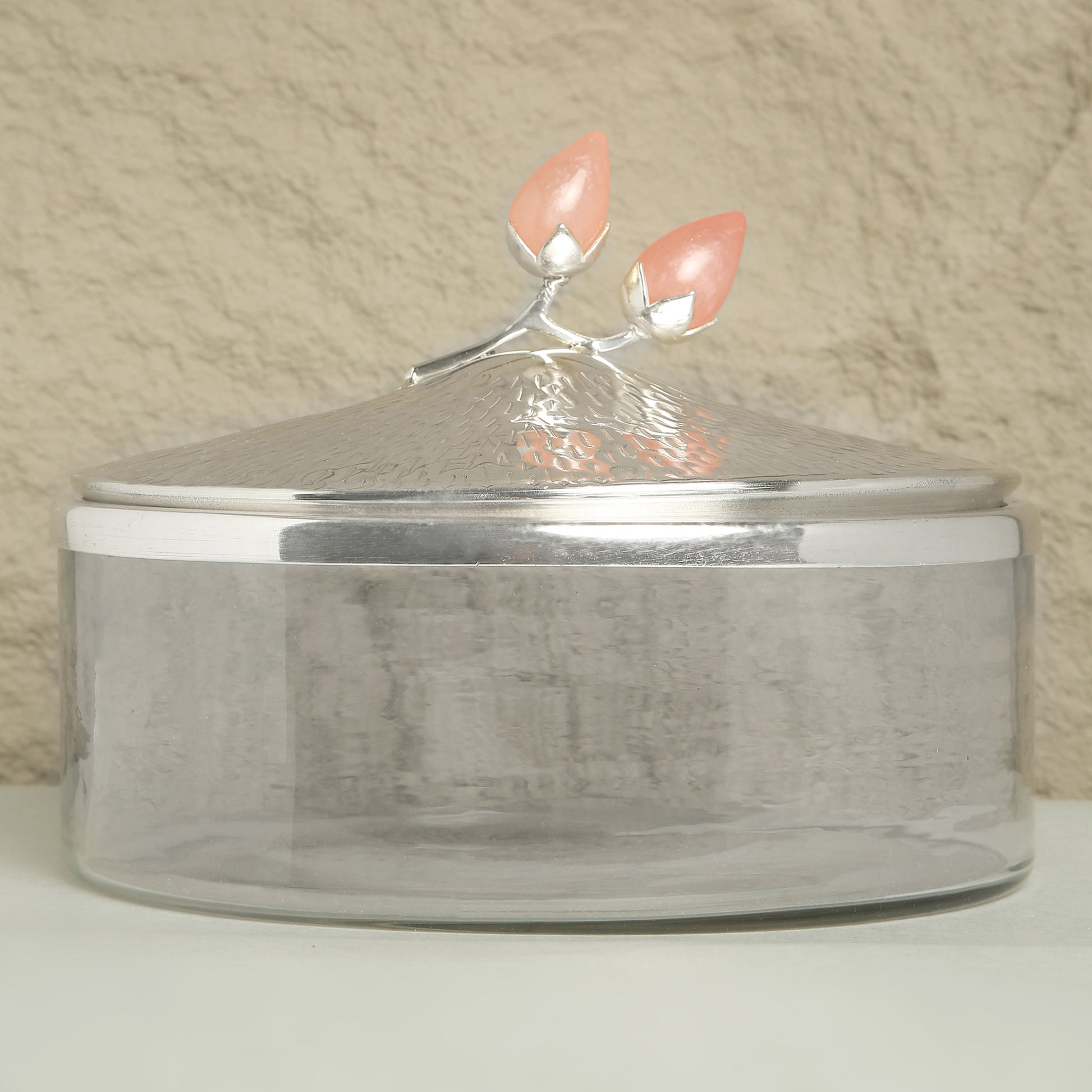 Silver container with a decorative lid featuring pink flowers on a beige background