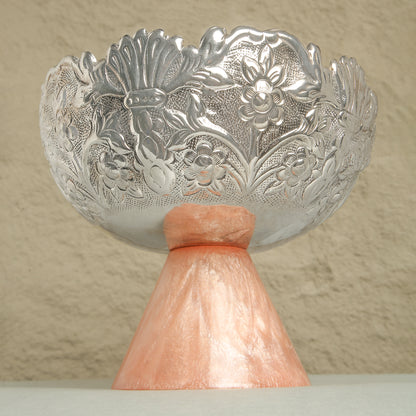 Decorative silver bowl with floral patterns on a beige background