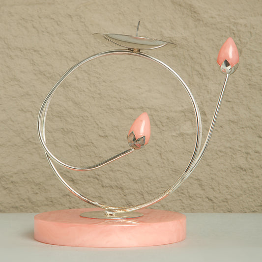 Decorative item with pink candle-like objects on a circular metal stand against a beige background